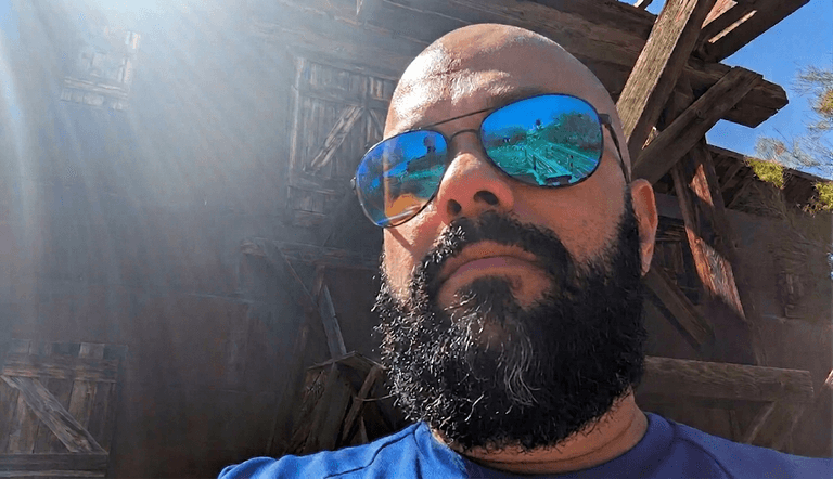 Rho Lall, a BI architect, in sunglasses against dark weathered timber